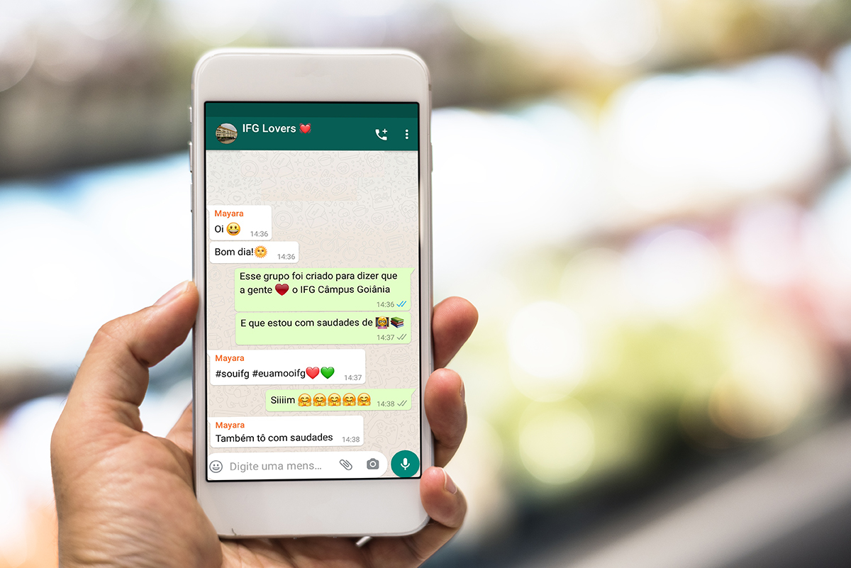 Pesquisa de iniciação científica mostra que uso dos emojis é influenciado pelo contexto social, cultural e até idade do usuário Imagem de uma pessoa segurando celular. Na tela uma conversa de whatsapp com mensagens usando emojis