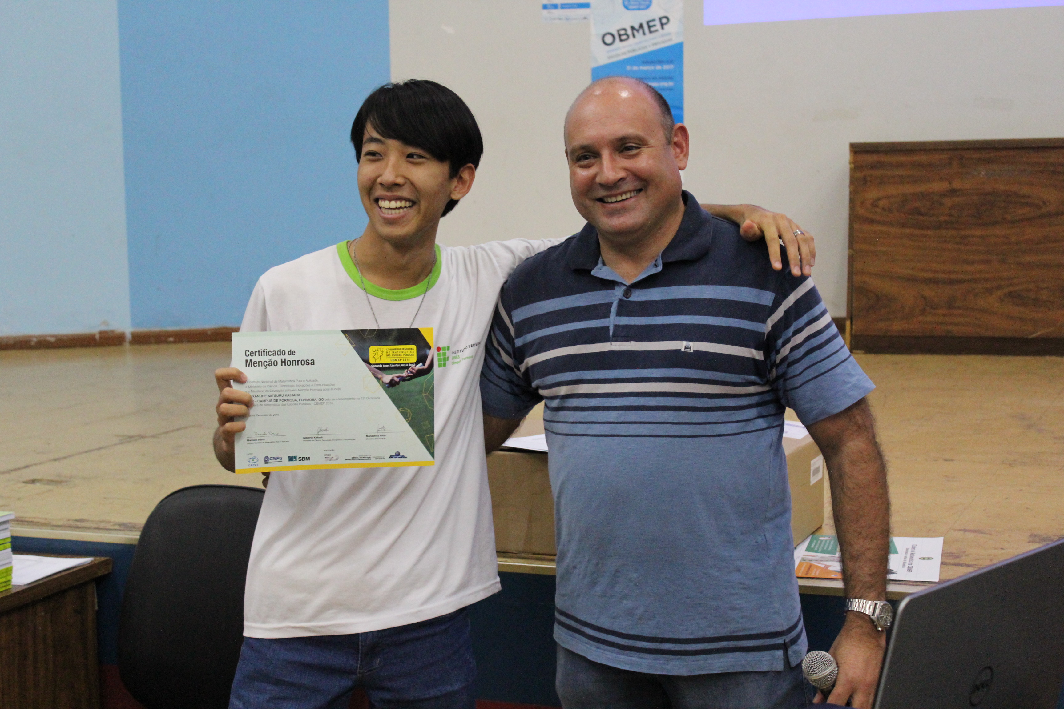 O aluno Alexandre Mitsuru Kaihara recebe premiação do coordenador regional da OBMEP